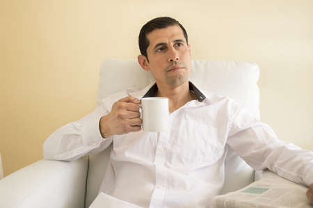 man sitting drinking tea and thinking while reading a newspaperの写真素材