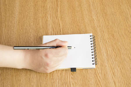 Womans hand with pen writing down notes in tableの写真素材