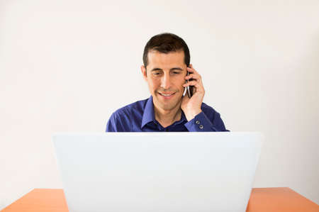 Successful business man talking with the phone while looking at the  laptopの写真素材