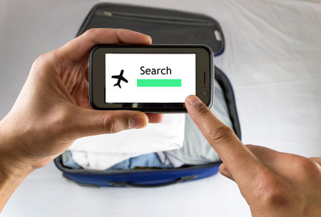 Businessman airplane booking with cellphone before close suitcaseの写真素材