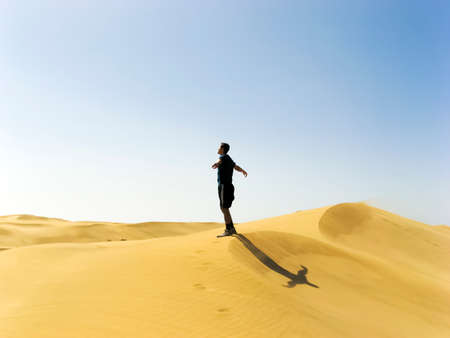 man stretching against seeing in the dunes in Maspalomas Gran Canaria Spainの写真素材