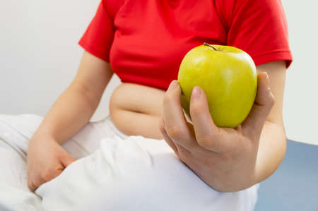 woman showing an apple to your diet and lose their fatの写真素材