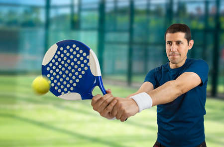  young male paddle tennis player standing and swatting the ballの写真素材