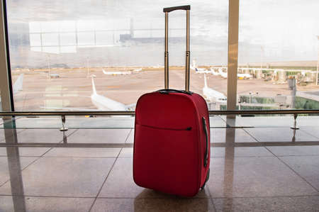 suitcase ready for travel at an airport with planes backgroundの写真素材