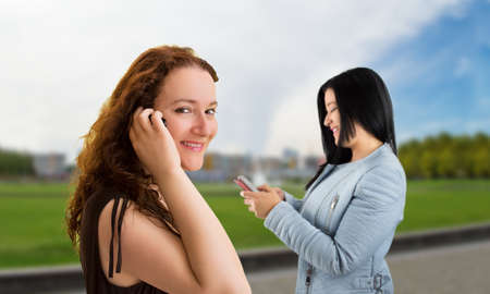 two happy women and using the phone on a streetの写真素材