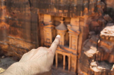 hands pointing to the facade of the al khazneh in petraの写真素材