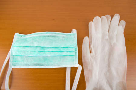 Horizontal view of new hygiene items consisting of latex gloves and mask on a wooden tableの写真素材