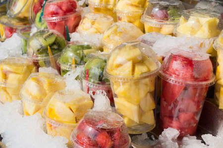 group of plastic glasses of fruit salad to take away on a stand at the street between iceの写真素材