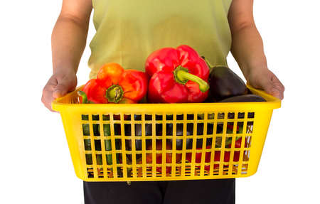 woman holding a basket with some vegetables tomatoes peppers and eggplantsの写真素材