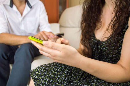 close up of woman reading message with man surfing with smartphone in backgroundの写真素材