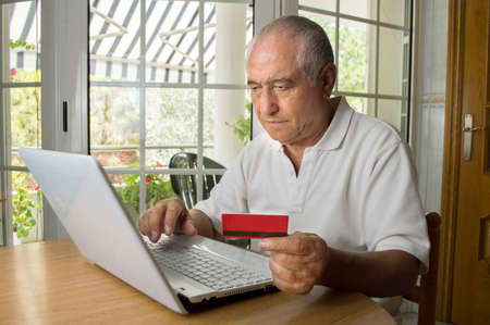 senior man shopping internet using his laptop in the roomの写真素材