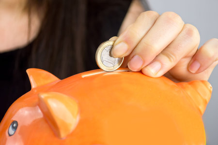 person Putting Coin In Piggy Bankの写真素材