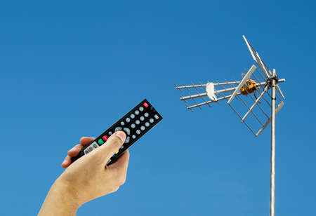 Hand holding a remote to activating a digital antenna tvの写真素材