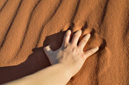 hand over the desert sand of a man thirsty and tiredの写真素材