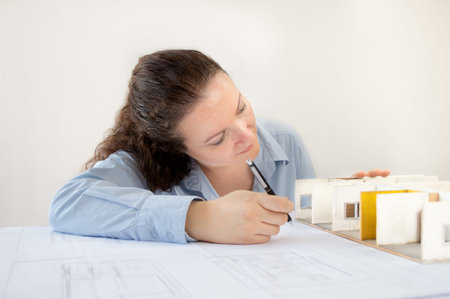 Close Up of an female architect adding to his planning next to a miniature