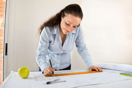 Close Up of an female architect adding to his planning next to a appleの写真素材