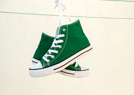 Vintage hanging green sneakers tied on pure white backgroundの写真素材