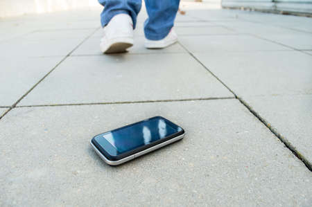 woman who loses the phone and falls in a cityの写真素材