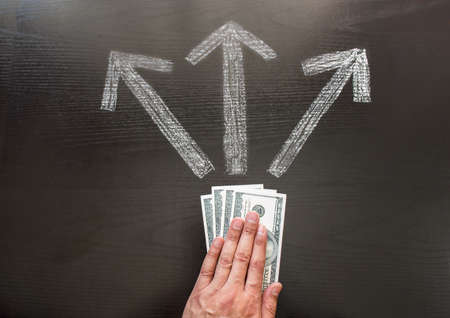 businessman making a decision for their money  in front of three arrows showing different waysの写真素材