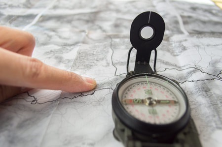topographic map with compass and man's hand planning a route or hiking trip on the mount