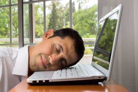 tired man falls asleep while working onlaptopの写真素材