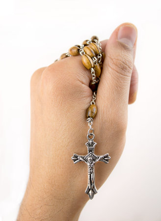 hand holding a wooden rosary praying to god