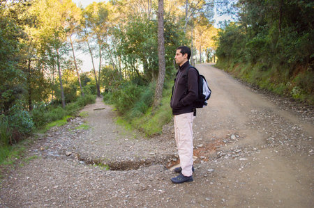 Male hiker looking to the side walking in forestの写真素材