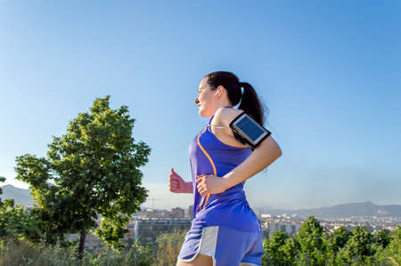 attractive brunette woman out for a run in the city listening to music on smartphoneの写真素材
