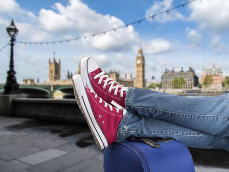 relaxed person with feet above the suitcase on arrival in londonの写真素材