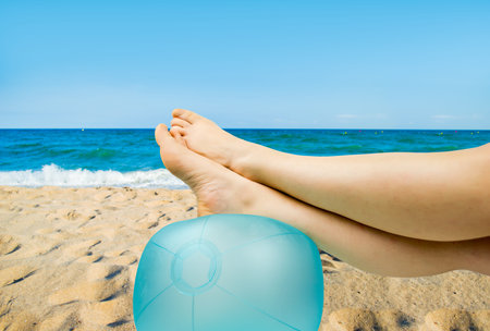relaxed person with feet above the ball on the beachの写真素材