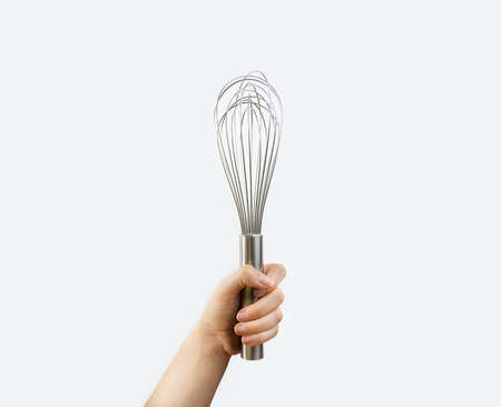 close up of hand holding a whisk with white backgroundの写真素材