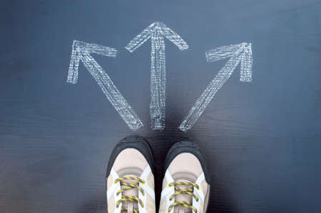 hiker man standing in front of three arrows showing different waysの写真素材