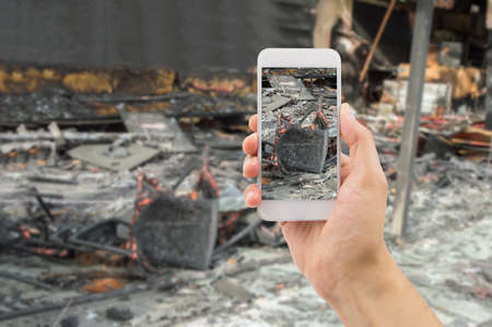 man photographing the damages of the home affected by the fire for home insuranceの写真素材