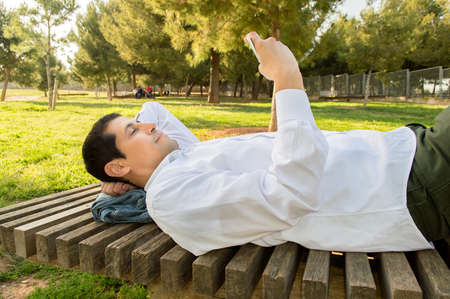 man using the smartphone in bank of the parkの写真素材