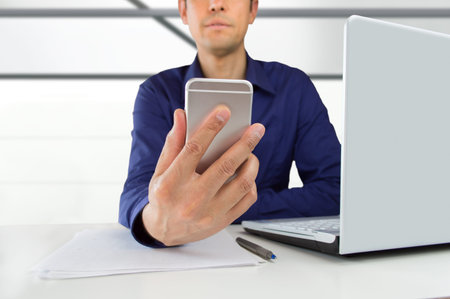 Businessman sending a text message to your smart phone at the office