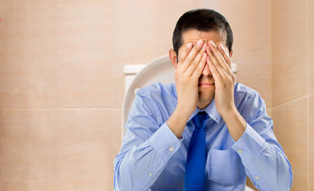businessman in the toilet with problems of constipationの写真素材