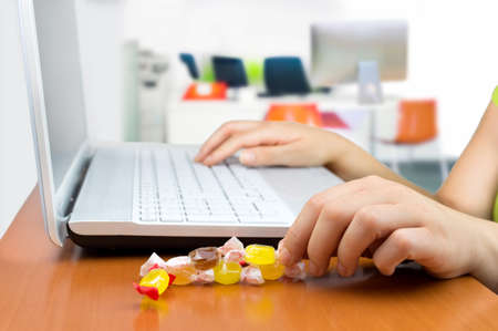 woman working at the laptop eating a candy sweetの写真素材