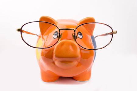 orange piggy bank is wearing glasses isolated on white backgroundの写真素材