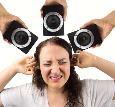 woman with hands in the ears disturbed by loud noise of the speakersの写真素材