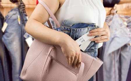woman trying to steal trousers from a clothing storeの写真素材