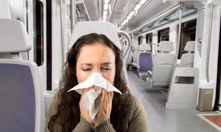 sick woman sneezing blowing nose in the train