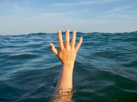 close up of hand drowning in a sea of waterの写真素材