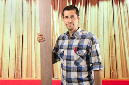 handyman standing in front holding a wooden plankの写真素材