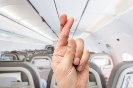 hand crossing the fingers like symbol of superstition to have good luck at the indoor of the plane