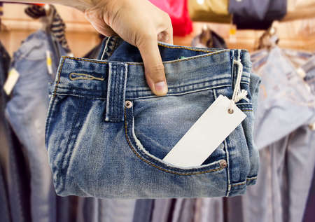 hand holding the jeans at the clothing storeの写真素材