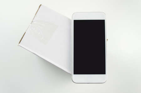 closeup of a package with the smartphone like a symbol of shopping through the mobile phone onlineの写真素材