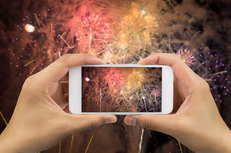 hands of man taking the photo to fireworks with the new smartphone