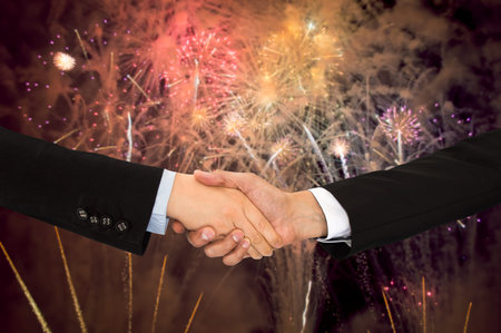 closeup of handshake between two business men with fireworks in the background like symbol of party...