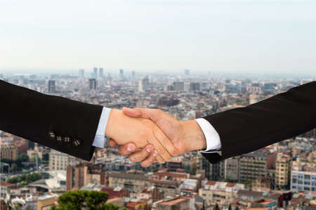two unrecognizable businessman and businesswoman shaking hands over a cityscape in the backgroundの写真素材