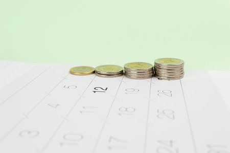 Studio shot of columns of coins over the calendar isolated on a white background